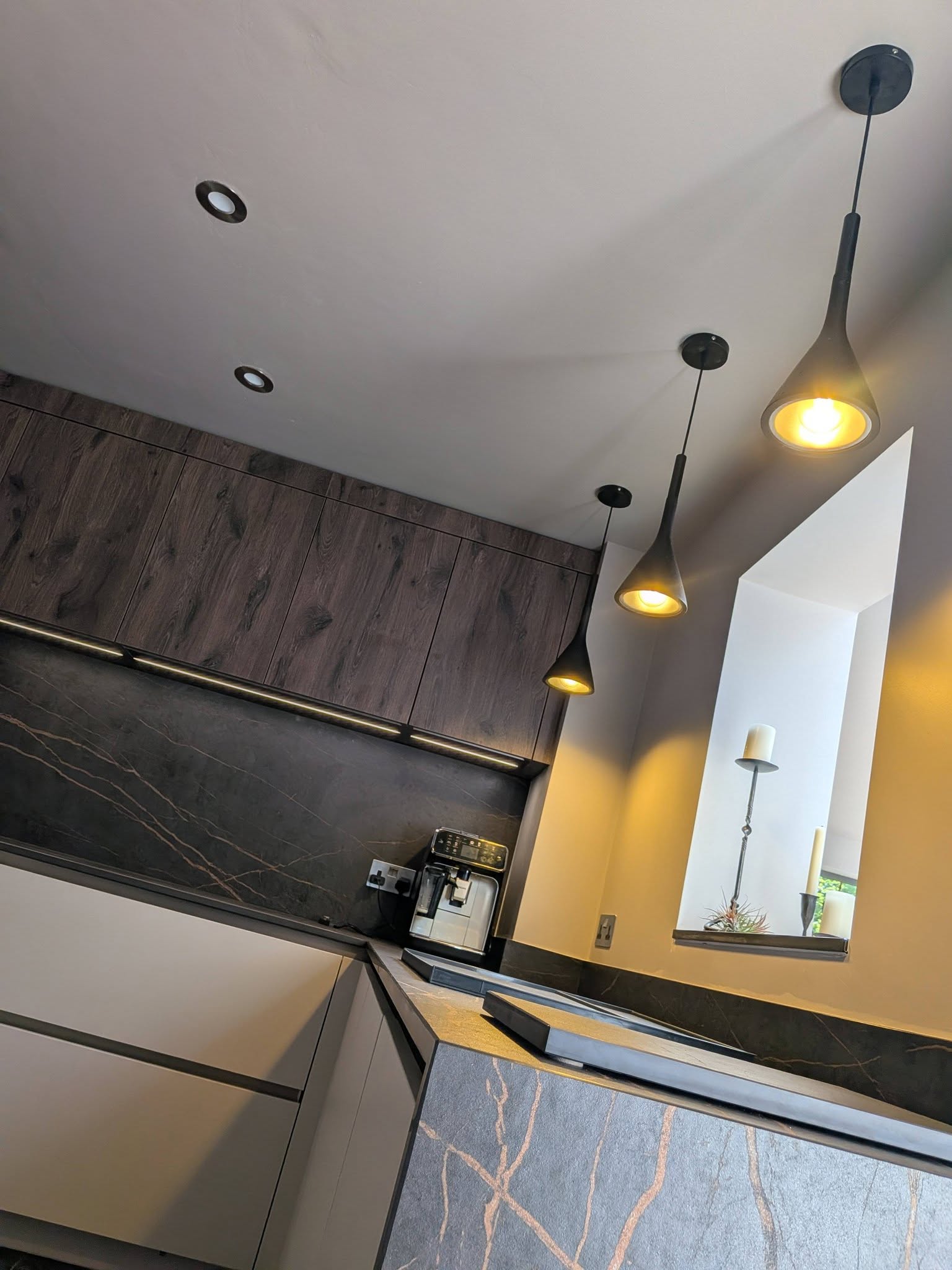 Completed kitchen with textured cabinetry, pendant lighting and pale worktops